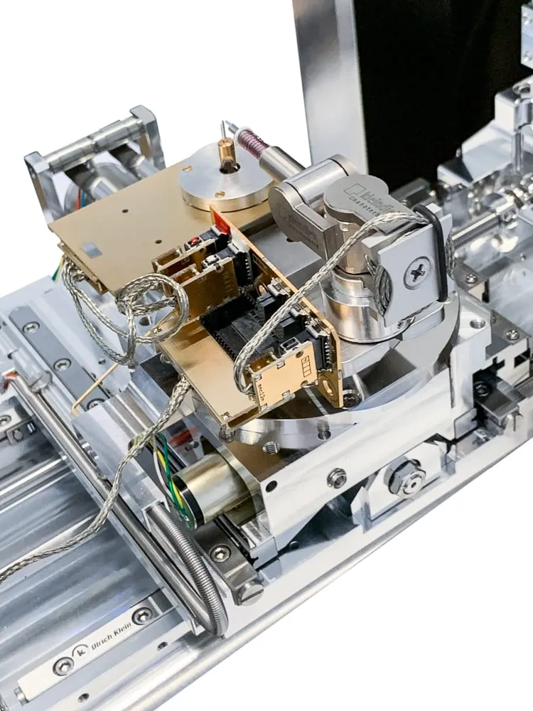 The nanolathe mounted in-chamber on an MM3A-EM rail, showing the linear-drive spring above the rotation motor and the gold circuit boards feeding it.