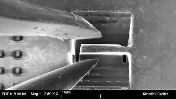 SEM image of the MGS2 jaws approaching a rectangular trench-cut sample on a chip, 10 µm scale bar.