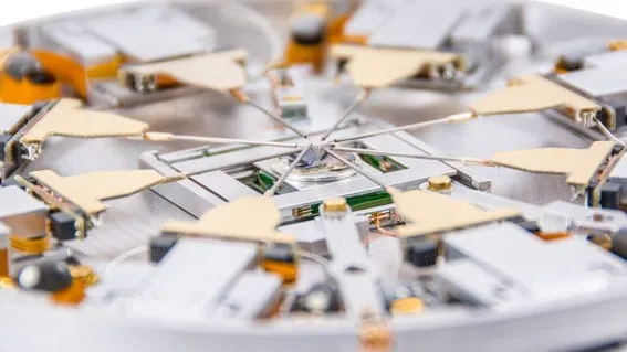 Top-down photo of the PS8 platform with eight MM4 manipulators arranged radially around a central chip.