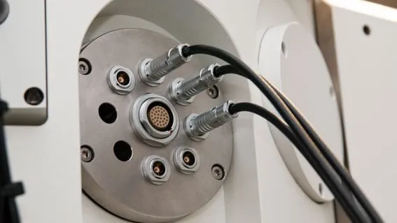 Photograph of a vacuum feedthrough panel with several triax and coaxial connectors and three shielded cables running to external instrumentation.