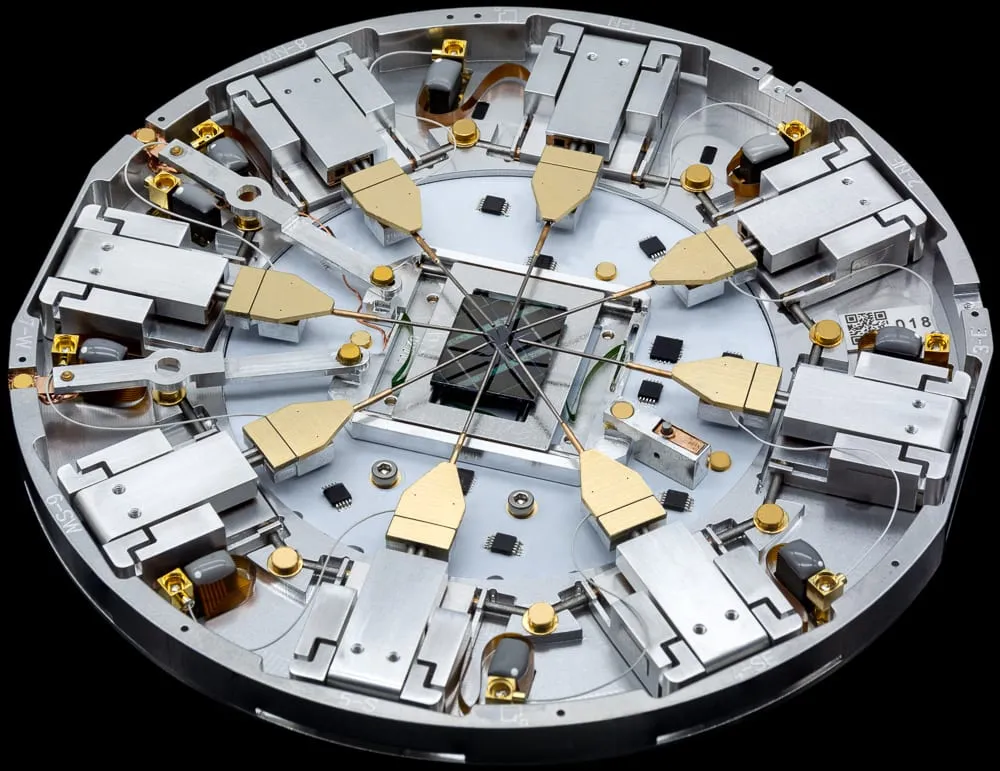 Perspective view of the PS8e Prober Shuttle — eight gold-tipped MM4 manipulators arranged radially around a central chip on a black stage.
