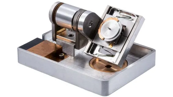 The ACT Anti-Curtaining Table — a compact machined-metal substage with a cylindrical drive at left and a tilted platform holding a round sample mount.